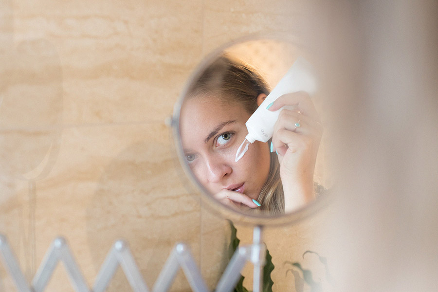 A person applying a white skincare cream to their face